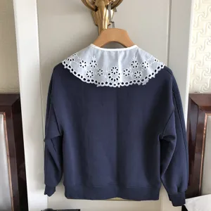 Dunkelblauer Pullover mit weißem, besticktem Spitzkragen, elegant und stilvoll.