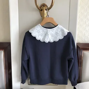 Detailansicht des dunkelblauen Sweatshirts mit grossem, weissen Spitzenkragen und Stickerei.