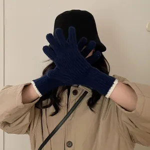 Close-up detail of knitted gloves, dark blue wool fabric with white ribbed cuffs for winter.