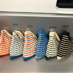 Gedetailleerd uitzicht van gebreide gestreepte schoudertassen in meerkleuren op metalen zit.