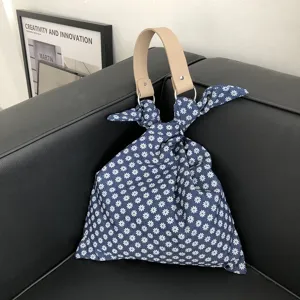 Sommerliche Stoff Handtasche mit Gänseblümchen Muster, Ledergriffen und modischem Knoten Design.