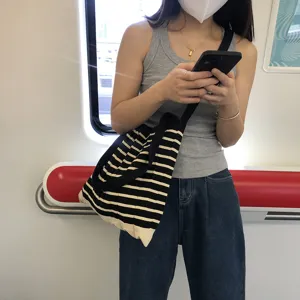Detailopname van gebreide gestreepte schoudertas, casual dagelijkse stijl in de metro.