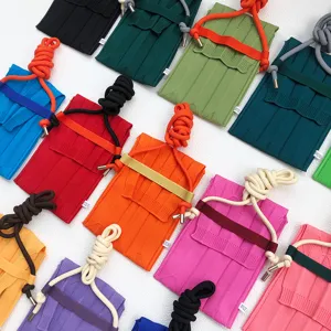 Detailansicht bunter geflochtener Mini-Handytaschen mit Plissee-Design und Tragekordel.