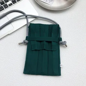 Detailansicht der dunkelgrünen Strick-Handytasche mit strukturierter Oberfläche und Gurt.