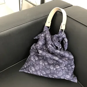 Detailansicht einer stilvollen Paisley-Stofftasche mit Ledergriff und elegantem Knotendesign.
