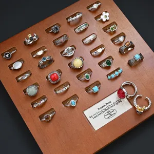 Detailed close-up view of vintage turquoise and gemstone rings assortment on wooden display board.