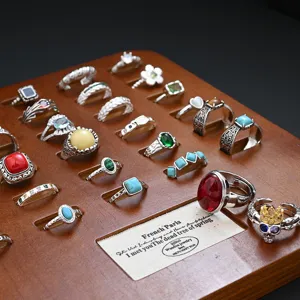 Vintage silver ring set with colorful stones and retro skull designs displayed on wooden rack.