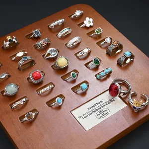 Detail shot of vintage gemstone rings displayed on a wooden tray, diverse retro styles.