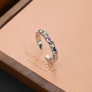 Detailed close-up shot of a vintage metallic open ring featuring colorful gemstone inlays.