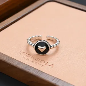 Detailed shot of vintage silver adjustable ring with black heart centerpiece and beaded band.