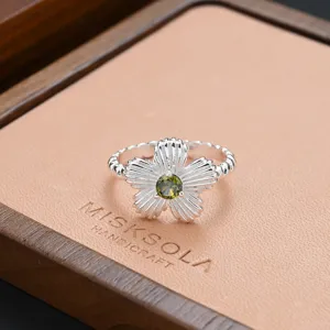 Silver flower ring detail with green gemstone, vintage aesthetic stylish statement jewelry piece.