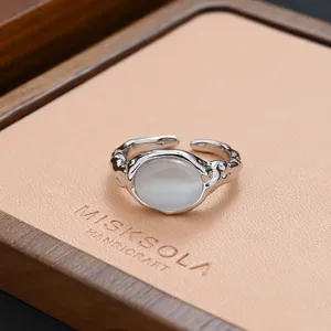 Close-up of niche silver irregular metal ring with white stone on tray, elegant detail shot.