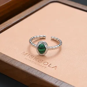 Detailed shot of an open silver ring with a green malachite stone on a jewelry tray.