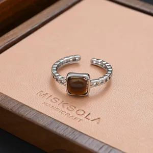Detailed shot of a stylish silver open ring with a square brown stone on a display pad.