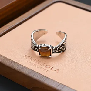Close-up detail of a vintage engraved open ring with a central brown stone, elegant retro style.