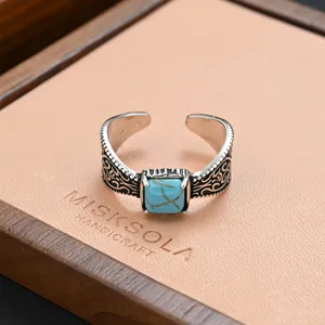 Vintage synthetic turquoise ring with retro carved details on wooden display tray.