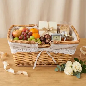 Weiden-Picknickkorb mit Stoffeinlage und Spitze, gefuellt mit frischem Obst und Geschenken.