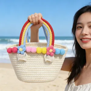 Stylish cotton rope woven beach handbag with colorful pom poms and cute floral decorations.