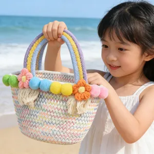 Cute cotton rope woven handbag with colorful pom poms and rainbow handle for beach travel.
