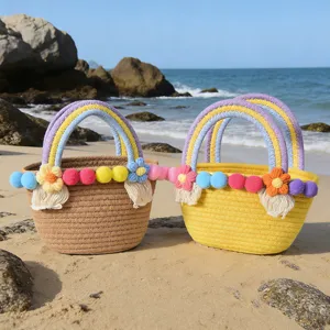 Cute handmade cotton rope woven handbag with colorful pom poms and flower decor for beach.
