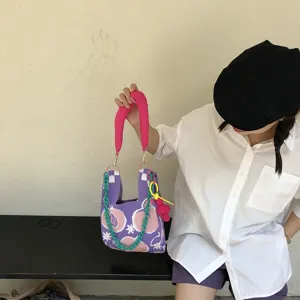 Detailed close-up showing the cute knitted tote bag featuring a pink handle and green chain.