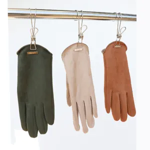 Detailed shot of faux suede winter gloves hanging on a rack, showing texture and metal tags.