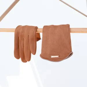 Brown faux suede winter gloves detail shot, soft texture with a decorative metallic tag.