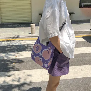 Detail shot of a cute purple knitted tote bag with peach pattern worn on the street.
