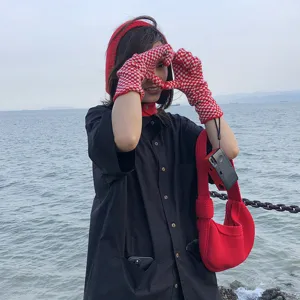 Red knitted checkered gloves and matching knot bag outdoor lifestyle detail view for women.