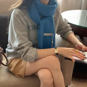 Gemütlicher blauer Strickschal aus Wolle kombiniert mit einem grauem Pullover für den Winter.