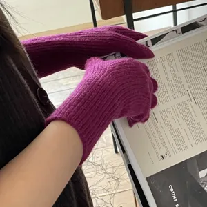 Detalle de guantes de invierno de punto acanalado magenta, textura de lana suave y cálida.