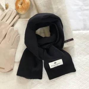 Close-up detail of the black wool scarf showcasing soft texture and brand label design.