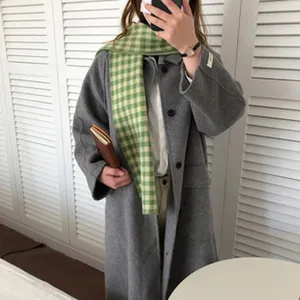 Bufanda a cuadros verde combinada con un abrigo de lana gris, estilo de invierno.
