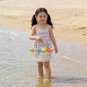 Charming beach scene showing details of the colorful woven cotton handbag with cute pom-poms.