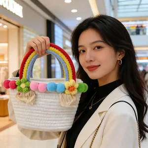 Handcrafted white woven handbag with colorful pom-poms and rainbow handles close up detail view.