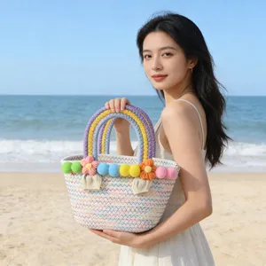 Detailed view of handmade woven straw beach bag with colorful pom poms and flower decor.