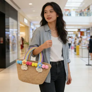 Woven straw tote bag with colorful pom-poms, perfect seaside beach handbag for women daily.