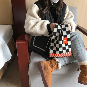 Vue détaillée d'un élégant sac à main en tricot à carreaux noir et blanc avec fleur.