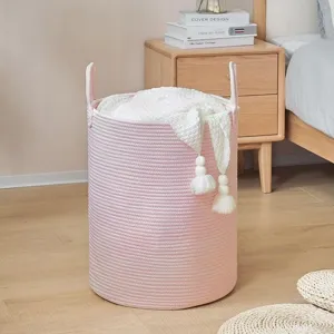 Pink woven cotton rope laundry basket with handles and cute tassels for home storage organization.