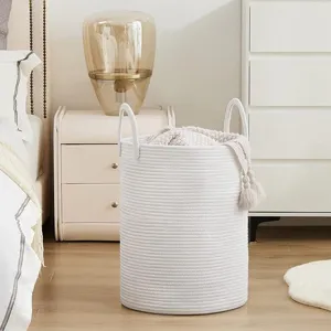 Detailed view of white woven cotton rope laundry basket placed in modern bedroom setting.
