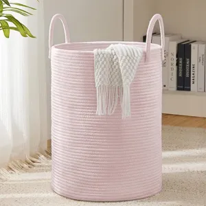 Close-up detail of the pink woven cotton rope laundry basket featuring dual handles and knit throw.