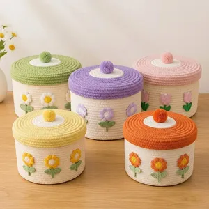 Detailaufnahme niedlicher Baumwollseil-Aufbewahrungskörbe mit bunten Blumenstickereien.