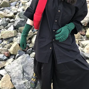 Detail shot of green black checkerboard knit gloves, stylish mid-length winter accessory.