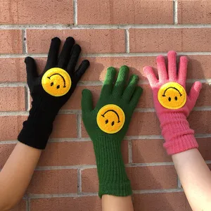 Détail de gants d'hiver en tricot avec de jolis écussons de smiley jaunes de plusieurs couleurs.