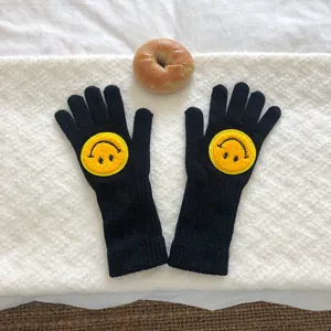 Gants d'hiver en tricot noir pour femmes avec jolie broderie de visage souriant.
