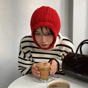 Detailed view of the red knit balaclava hat in a cozy cafe setting, soft and warm winter wear.