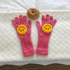 Jolis gants tricotés rose pour femmes avec un adorable visage souriant jaune pour hiver.