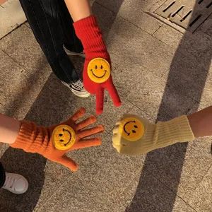 Gants d'hiver tricotés confortables avec un joli patch visage souriant jaune en gros plan.