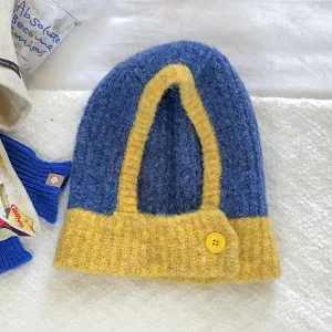 Blue and yellow colorblock knitted balaclava cap detail showing woolen texture and button accent.