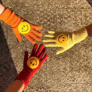 Vue détaillée de gants en tricot colorés avec de charmants patchs smiley d'hiver.